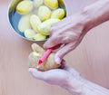 Close up of man holding and peeling potato. Hands cutting potatoes at kitchen to prepare a recipe