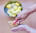 Close up of man holding and peeling potato. Hands cutting potatoes at kitchen to prepare a recipe