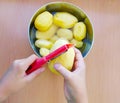 Close up of man holding and peeling potato. Hands cutting potatoes at kitchen to prepare a recipe