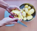 Close up of man holding and peeling potato. Hands cutting potatoes at kitchen to prepare a recipe