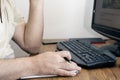 Caucasian man holding a pen in front of a monitor with his keyboard behind it and a notepad underneath Royalty Free Stock Photo