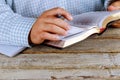 Man is holding a pen in his hand with an open Holy Bible lying in fornt of him Royalty Free Stock Photo