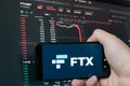 Man holding phone with FTX logo. Global fall of cryptocurrency graph - FTT token fell down on the chart crypto exchanges on app