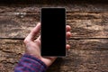 Man holding a phone in his hand on the wooden background Royalty Free Stock Photo