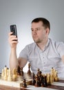 Man holding a phone in their hands and playing chess Royalty Free Stock Photo