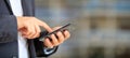 Man holding phone. Young businessman in business wear using a mobile, closeup view on smartphone, banner