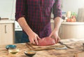 Man holding of piece of beef meat on a wooden table