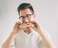 Man holding a piece of hamburger. student eats fast food. not helpful food. very hungry man. Nerd is wearing glasses. Royalty Free Stock Photo