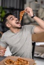 Man holding piece of pizza over open mouth