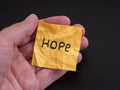 A man holding a piece of yellow paper with the word Hope on it in his hand Royalty Free Stock Photo