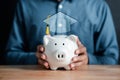 Man holding piggy bank with graduation cap. saving money for future education. Education fees and cost of college graduate. Royalty Free Stock Photo