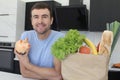 Man holding piggy bank next to groceries Royalty Free Stock Photo