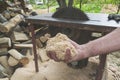 Man holding pile of fresh sawdust in his hand, with chopped wood and circular table saw in the background. Close up of wood