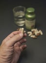 Man holding a pills with a glass of water and a bottle of vitamin.