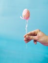 Man holding a pink Easter egg on a stick on a blue background Royalty Free Stock Photo