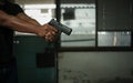 Man holding a pistol, standing in a room in black, pointing and aiming a gun at a target. concept of assassination, murder, Royalty Free Stock Photo