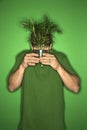 Man holding plant in front of his face.