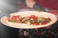 Man holding a plate with lavash, grilled meat and vegetables