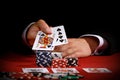 Man holding playing cards over poker chips on red table Royalty Free Stock Photo