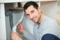 man holding plumbing pipes underneath sink