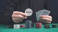 Man holding poker chips and cards on the green table