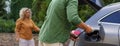 Man holding power supply cable, while his wife waiting for car charging at electric vehicle charging station, closeup Royalty Free Stock Photo