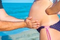 A man is holding a pregnant woman by the stomach on the beach, by the sea. The concept of family, love, new life and peace, the ex Royalty Free Stock Photo