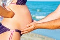 A man is holding a pregnant woman by the stomach on the beach, by the sea. The concept of family, love, new life and peace, the ex Royalty Free Stock Photo