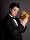 A man holding present box in formal black tux