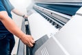 man holding printable material on alarge format printing plotter