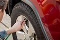 Man holding pump pressure gauge, checking air pressure and filling air in the tires of the car