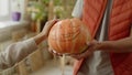 A man is holding a pumpkin in his hands and a lady is stroking it