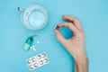 The man is holding a red pill. Blue background. A glass of water and a box of pills when traveling. Medical background Royalty Free Stock Photo