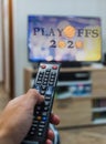 Man holding a remote control watching basketball playoffs