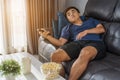 Man holding remote control and watching TV while sitting on sofa Royalty Free Stock Photo