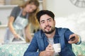 man holding remote control while woman iron