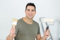 man holding roller brush and ordinary paint brush Royalty Free Stock Photo