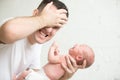 Man holding a screaming newborn, his hand at his head Royalty Free Stock Photo