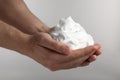 Man holding shaving foam on light grey background, closeup