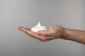 Man holding shaving foam on light grey background, closeup