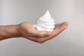 Man holding shaving foam on light grey background, closeup