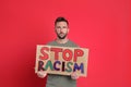 Man holding sign with phrase Stop Racism on red background Royalty Free Stock Photo
