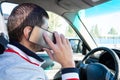 A man holding a silver mobile phone near his ear and talking on it while driving. Danger of using the phone in a car Royalty Free Stock Photo