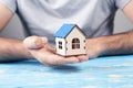 a man holding a small house in front of a table Royalty Free Stock Photo