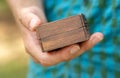 Man holding a small simple generic wooden box container in hand, detail, closeup, mystery gift box, presents and gifts. Box for