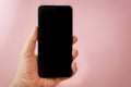 Man holding smart phone in his hand, with blank black screen and pink background Royalty Free Stock Photo