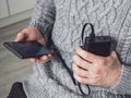 A man is holding a smartphone connected to a power bank. Additional power supply for modern devices. Portable charger and phone in Royalty Free Stock Photo