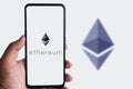 Man holding smartphone with Ethereum logo agains the isolated background