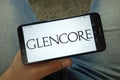 Man holding smartphone with Glencore plc company logo