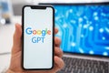 A man is holding a smartphone with a Google GPT neural network logo on the screen